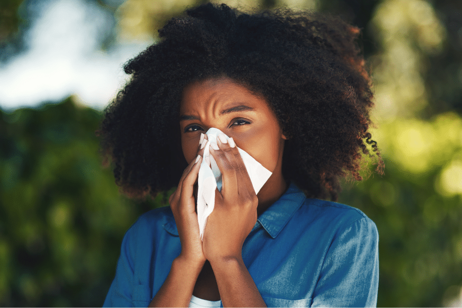 A patient with untreated sinus issues snnezing into a tissue in Houston