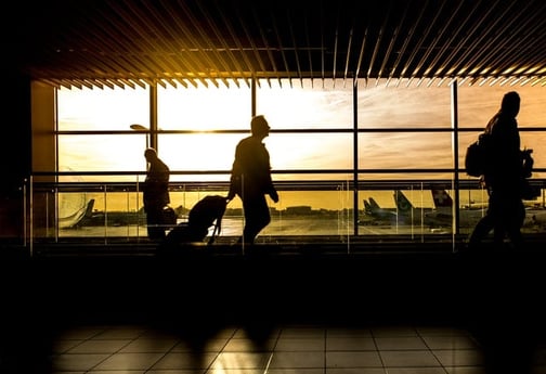 Person wheeling a suitcase through an airport 