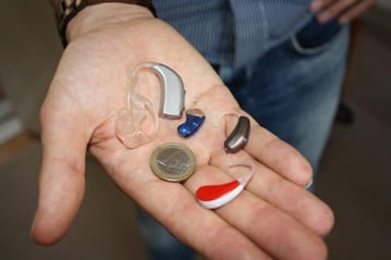Different hearing aid types in a persons palm
