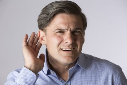Man putting hand up to ear trying to listen